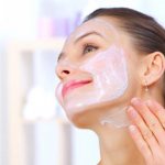 Woman over 40 applying mask to face